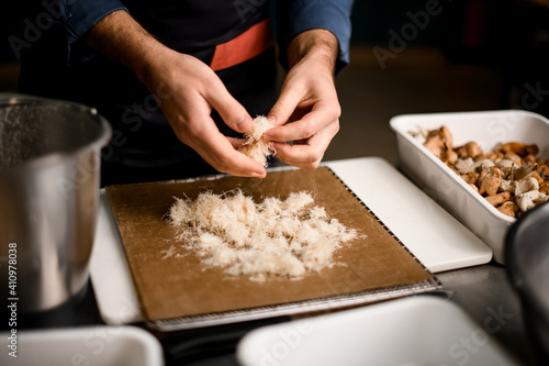 close-up of hands of male chef who lays ingredients for dish on cutting board