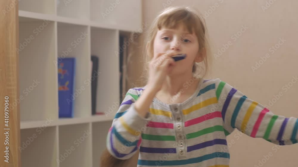 Happy girl playing harmonica home interior Happy girl playing harmonica home interior
