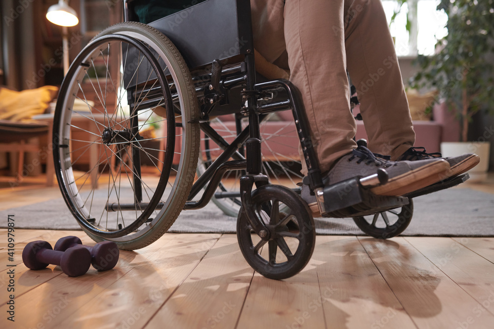 Obraz premium Close-up of man sitting in wheelchair and exercising with dumbbells at home