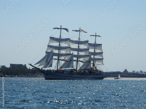 A sailing ship with white sails on three masts at sea. The concept of a cruise, vacation at sea, sailing, yachting.