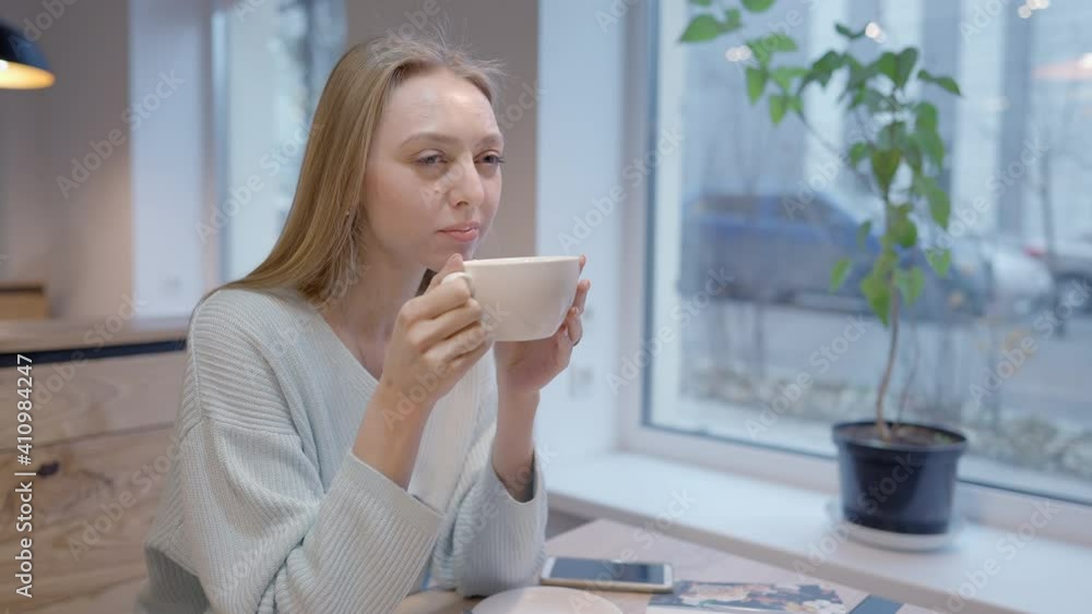Middle shot of happy relaxed Caucasian woman drinking tasty coffee in cafe or restaurant. Portrait of carefree joyful lady enjoying hot drink indoors at breakfast or lunch. Lifestyle concept. Middle shot of happy relaxed Caucasian woman drinking tasty coffee in cafe or restaurant. Portrait of carefree joyful lady enjoying hot drink indoors at breakfast or lunch. Lifestyle concept.