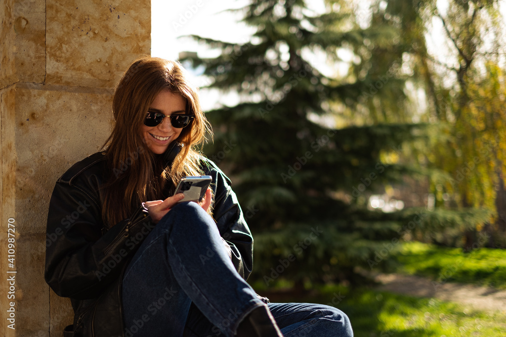 Young redhead woman browsing smartphone outdoors 