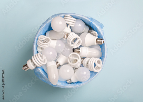energy saving light bulbs in a bucket in disposable plastic garbage bag on blue background for recycling. LED bulbs. Energy saver. Eco friendly. Energy-effective lamps. Reduce and save the planet