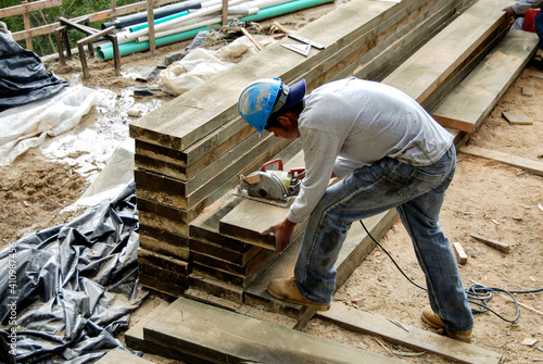 Worker cutting large beams with a power saw