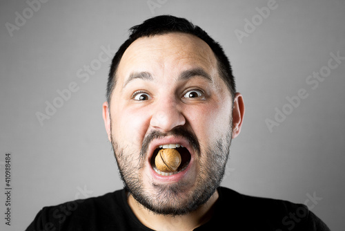 a man tries to crack a nut with his teeth. the concept of a complex problem or strong teeth