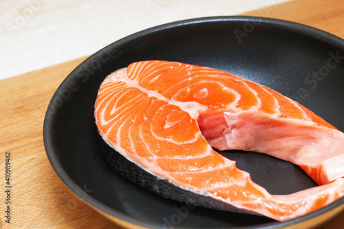 Fresh salmon steak in a black pan. Preparing for cooking.