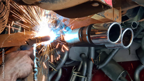  Mechanic or welder is fixing a car exhaust system by welding the exhaust pipe photo