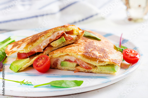 Tasty breakfast with quesadilla and eggs. Mexican cuisine. Trending food with omelet, cheese, tomatoes, avocado. Simple and easy lunch.