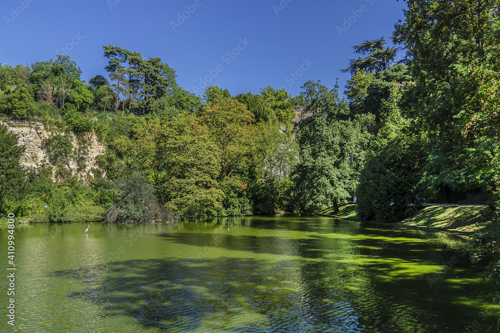 The artificial lake in Parc des Buttes-Chaumont - Public Park situated in northeastern Paris. It opened in 1867; it is fifth-largest park in Paris. France. The artificial lake in Parc des Buttes-Chaumont - Public Park situated in northeastern Paris. It opened in 1867; it is fifth-largest park in Paris. France.