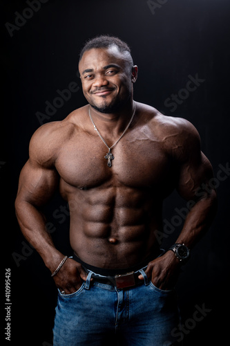 Athlete in phototstudio. Very muscular athlete man shows body to the camera. Perfect muscules. Black background.