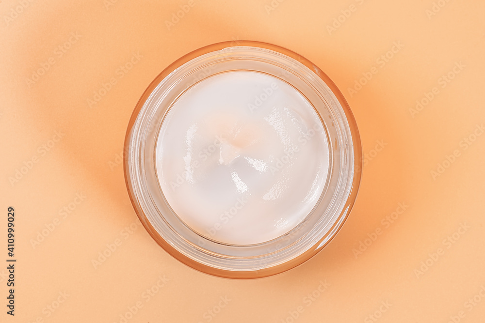White moisturizer in a glass jar top view on beige White moisturizer in a glass jar top view on beige