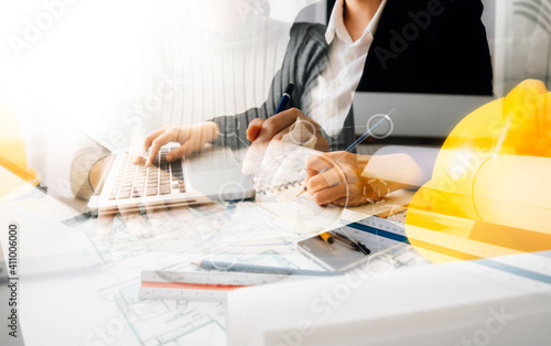 Two colleagues discussing data working and tablet, laptop with on on architectural project at construction site at desk in office