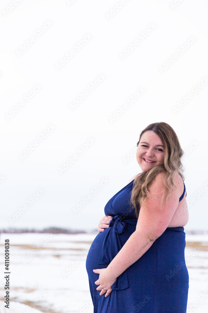Beautiful pregnant brunette model wearing flowing dress surrounded by winter landscape Beautiful pregnant brunette model wearing flowing dress surrounded by winter landscape