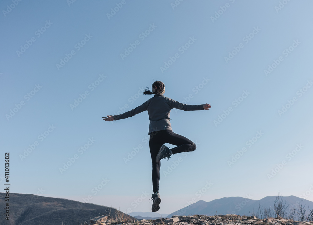 The girl on the top of the mountain jumps for joy with her arms wide open. Flight and levitation The girl on the top of the mountain jumps for joy with her arms wide open. Flight and levitation