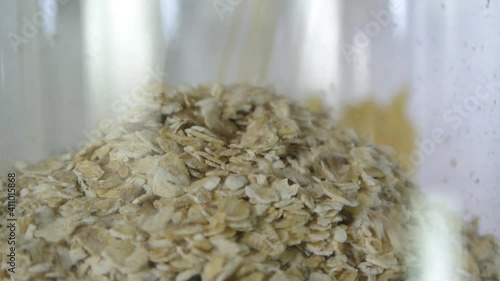 Oatmeal is poured into a transparent glass jar and fills it, shot up close with a shallow depth of field