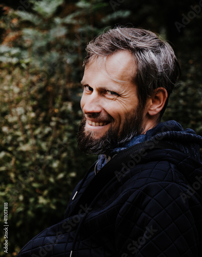 Smiling handsome young or a middle-aged Caucasian man portraited in the city, with white skin, grey and black hair having a friendly and confident look on his face. Background with fall moody colours 