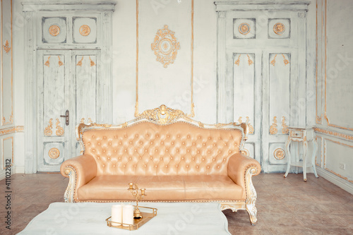 very rich interior of the apartment with golden decorations on the walls in the Baroque style and luxury furniture with gold paint.