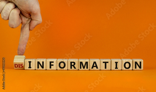 Information or disinformation symbol. Businessman flips a cube and changes the word disinformation to information. Orange background, copy space. Business and information or disinformation concept. photo