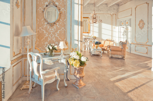 rich apartment interior with golden baroque decorations on the walls and luxury furniture. the room is flooded with the rays of the setting sun © 4595886