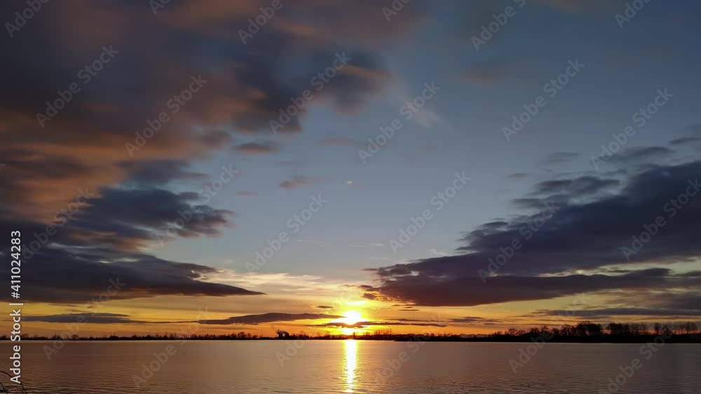 Day to night time lapse sun moving in clouds on moody sky over the lake Day to night time lapse sun moving in clouds on moody sky over the lake