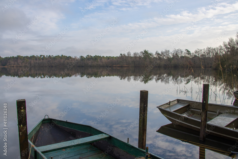 Fishermen boats in a lake during autumn time. Clouds reflecting on water.