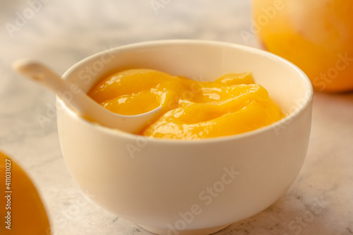 Composition with delicious Yellow lemons and Lemon curd in a sausepan white bowl on marble background