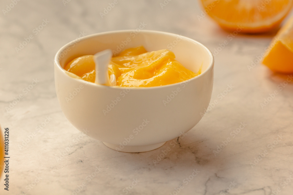 Composition with delicious Yellow lemons and Lemon curd in a sausepan white bowl on marble background Composition with delicious Yellow lemons and Lemon curd in a sausepan white bowl on marble background