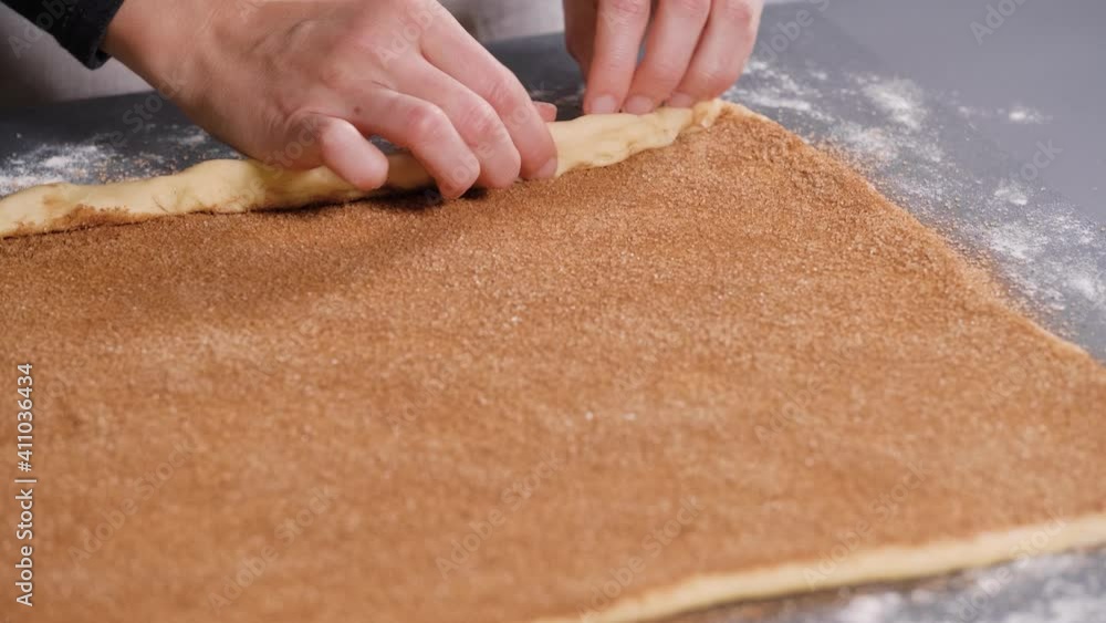 Woman rolling out dough for buns with cinnamon Woman rolling out dough for buns with cinnamon