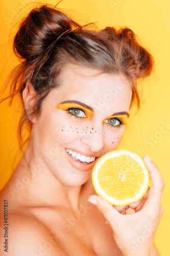 Frau mit Orange Obst gelb weiße Zähne Make Up braune Haare lustig frech freundlich