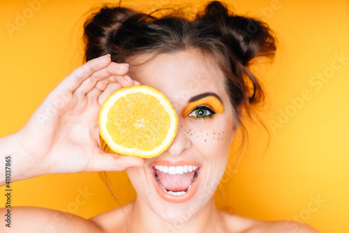 Frau mit Orange Obst gelb weiße Zähne Make Up braune Haare lustig frech freundlich