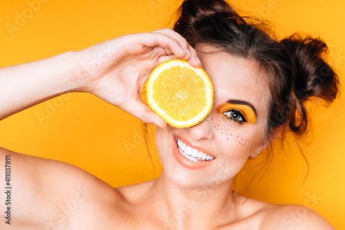 Frau mit Orange Obst gelb weiße Zähne Make Up braune Haare lustig frech freundlich