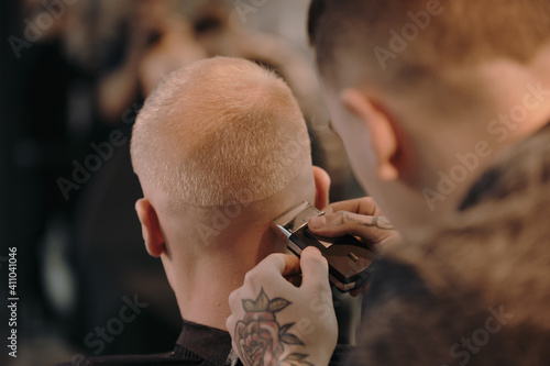Man barber cutting hair of his client in a barbershop, abstract view
