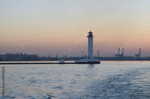 lighthouse at sunset on a warm summer evening with an industrial backdrop.
