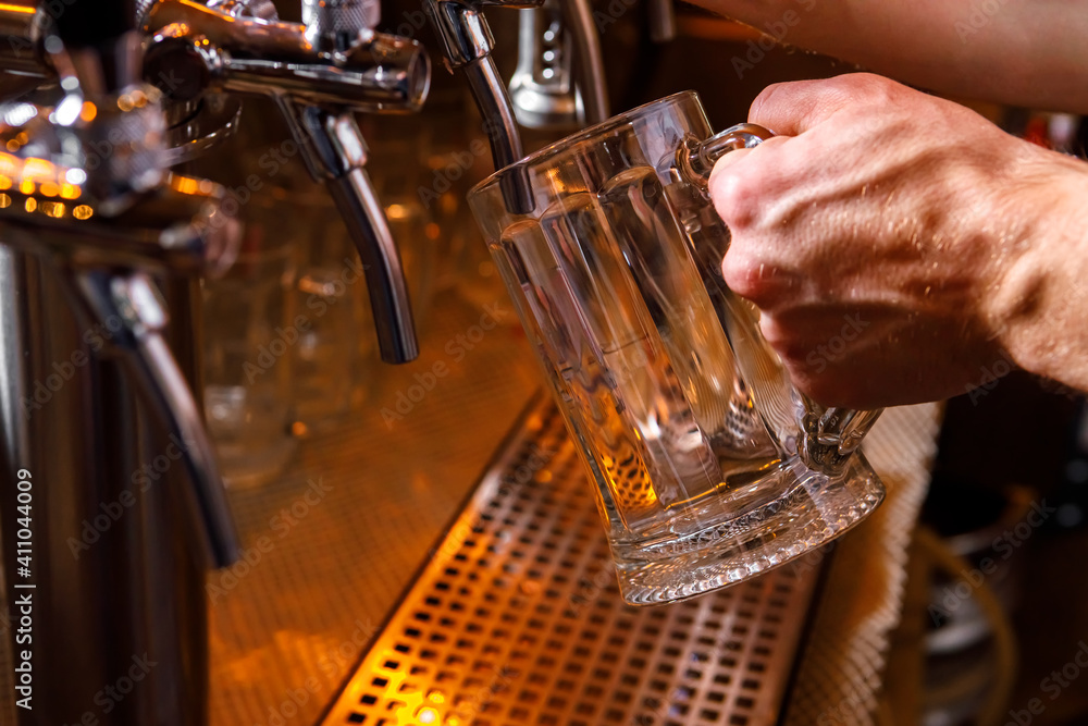 Pouring beer into a mug in a beer bar close-up. Beer bottling in the restaurant. The bar counter.