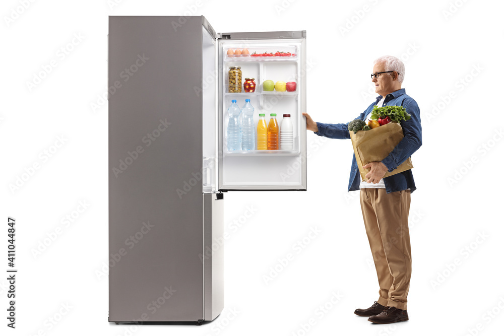 Full length profile shot of a mature man with a grocery bag opening a fridge Full length profile shot of a mature man with a grocery bag opening a fridge
