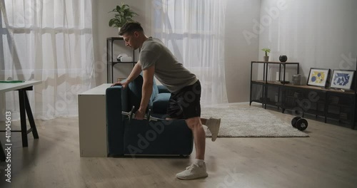 jock is training at home, lifting dumbbell by one hand, workout for biceps and triceps, healthy lifestyle and sport activity photo