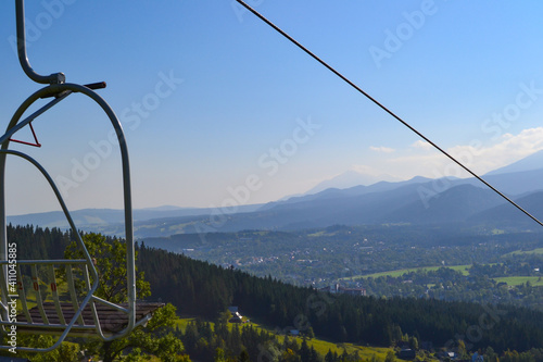Summer lifts on a mountainside with mountains and horizon in the background photo