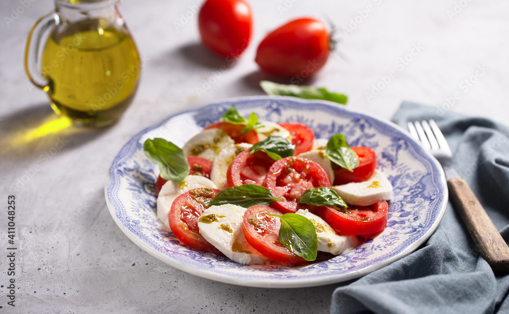Caprese salad. Italian famous salad with fresh tomatoes, mozzarella cheese and basil Caprese salad. Italian famous salad with fresh tomatoes, mozzarella cheese and basil