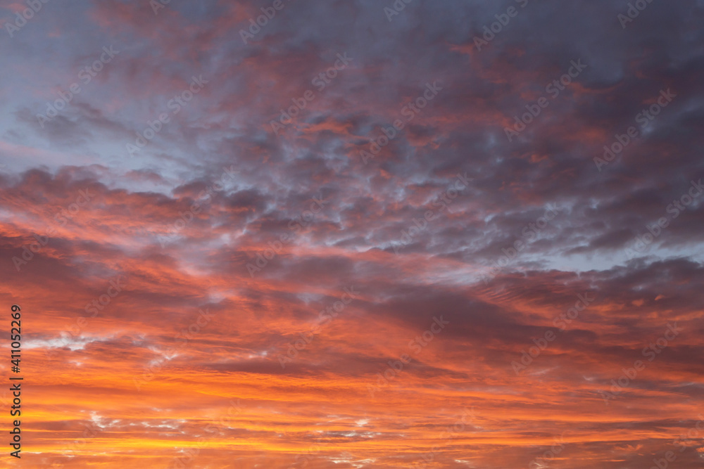 Epic Dramatic sunrise, sunset orange red yellow pink clouds against blue sky background texture