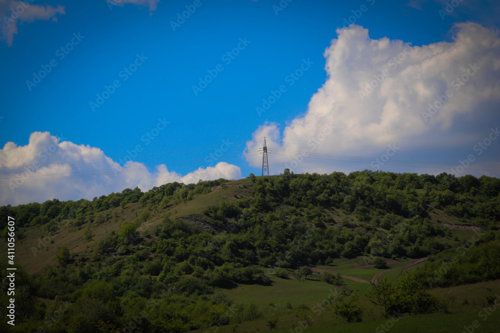 A electricity pole on a hill land scape in the middle of nowhere in the nature.