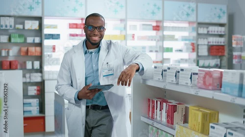 Wallpaper Mural Pharmacy: Portrait of Professional Confident Black Pharmacist Uses Digital Tablet Computer, Checks Inventory of Medicine, Looks at Camera and Smiles Charmingly. Drugstore with Health Care Products Torontodigital.ca