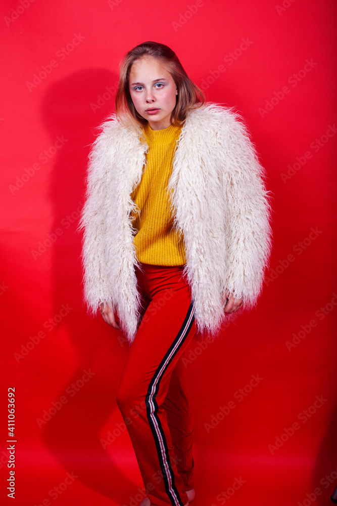 young pretty fashion teenage girl on bright red background, happy smiling lifestyle people concept young pretty fashion teenage girl on bright red background, happy smiling lifestyle people concept