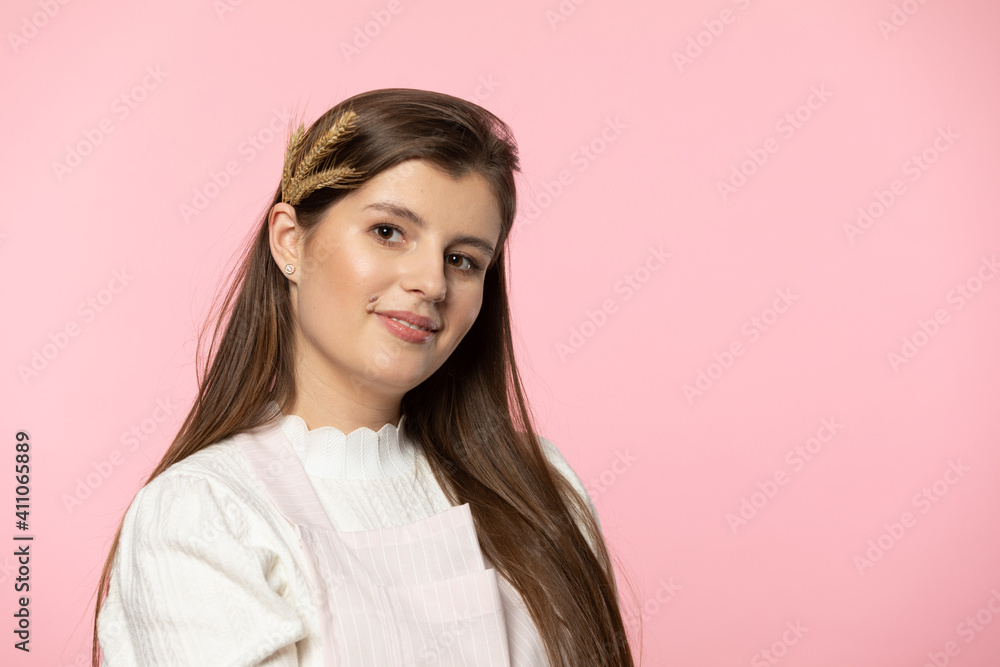 Portrait of an attractive young girl with colossi of grain in her hair. The whole is isolated from a uniform light pink background. Portrait of an attractive young girl with colossi of grain in her hair. The whole is isolated from a uniform light pink background.