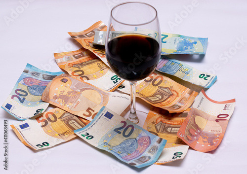 glass of wine with a lot of money on the floor, euro notes of five, fifty, twenty and ten.