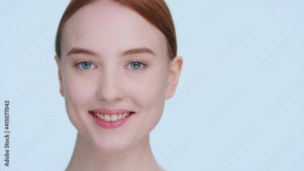 Close-up beauty portrait of young ginger woman demonstrates her face skin elasticity, touching her cheek with fingers Close-up beauty portrait of young ginger woman demonstrates her face skin elasticity, touching her cheek with fingers
