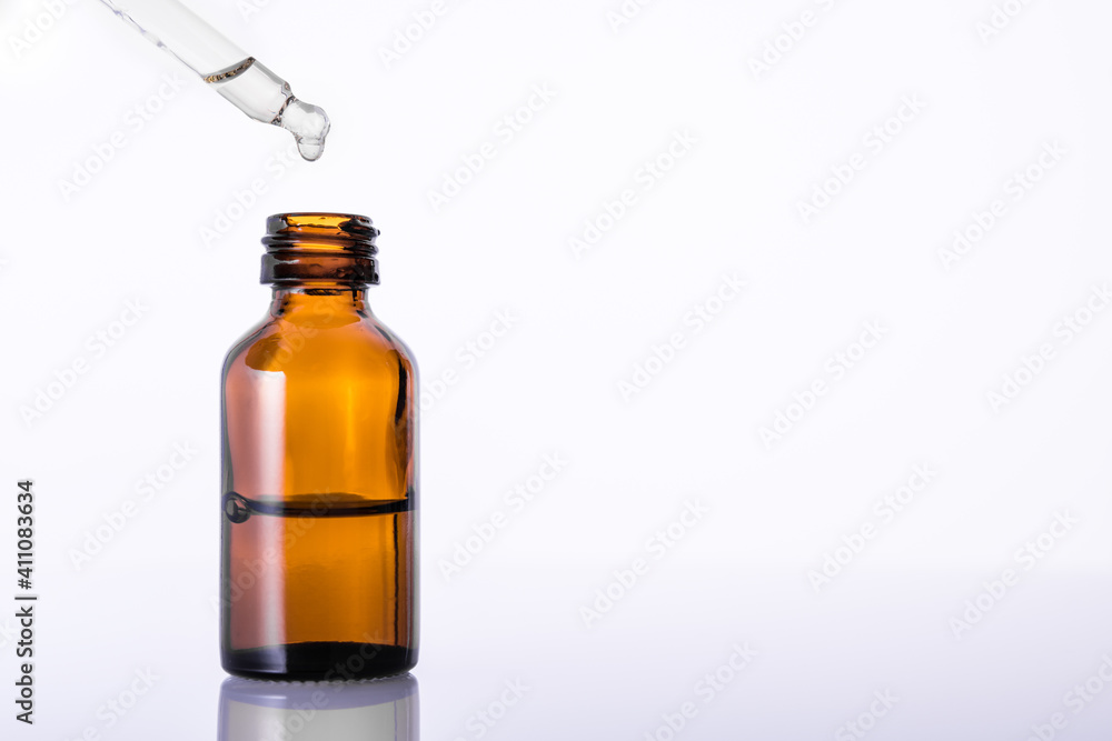 Essential oil for aromatherapy. Brown glass bottle with medicine dropper or pipette. White background. Copy space. Essential oil for aromatherapy. Brown glass bottle with medicine dropper or pipette. White background. Copy space.