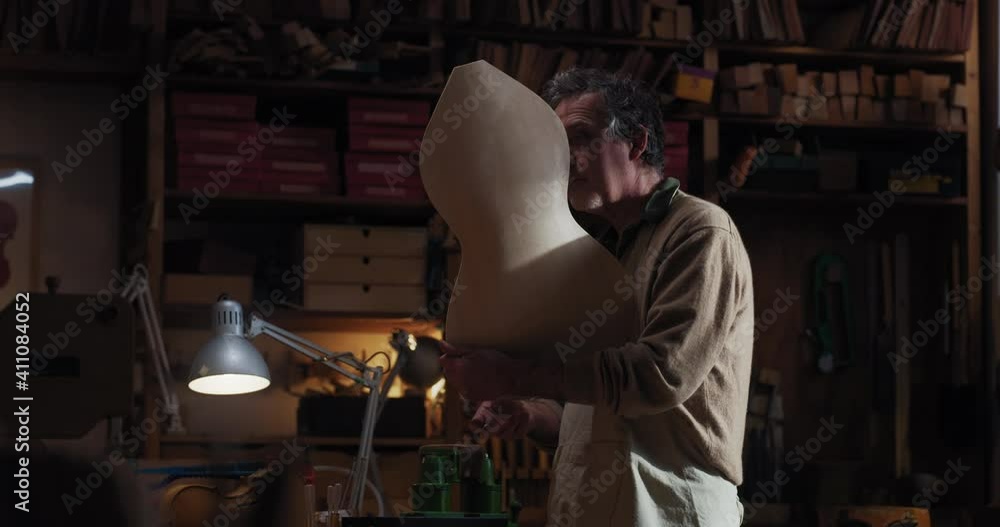 Cinematic shot of master artisan luthier working on creation of handmade fine quality wood violin in creative workshop. Concept of spiritual instrument, handmade, art, orchestra, artisan, music. Cinematic shot of master artisan luthier working on creation of handmade fine quality wood violin in creative workshop. Concept of spiritual instrument, handmade, art, orchestra, artisan, music.