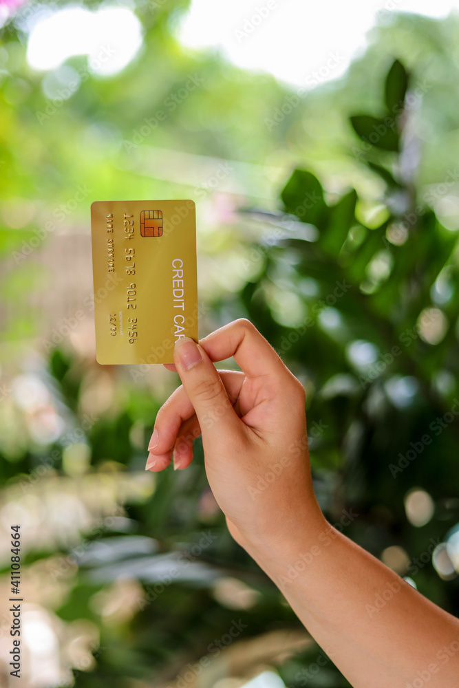 The person is holding a gold credit card, a credit card can be used to pay for goods and