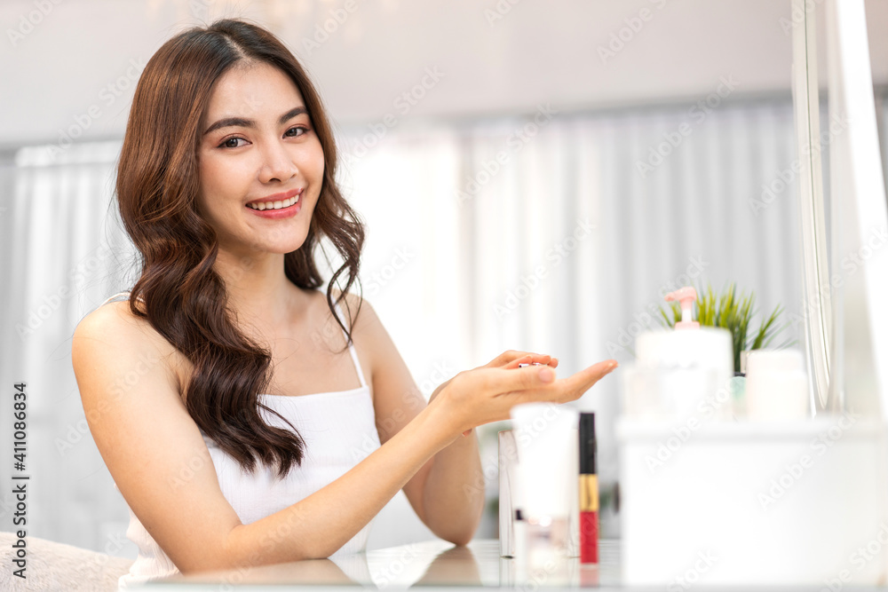 Smiling of young beautiful pretty asian woman clean fresh healthy white skin looking at camara.asian girl holding body lotion and applying moisturizing cream at home.spa and beauty concept Smiling of young beautiful pretty asian woman clean fresh healthy white skin looking at camara.asian girl holding body lotion and applying moisturizing cream at home.spa and beauty concept