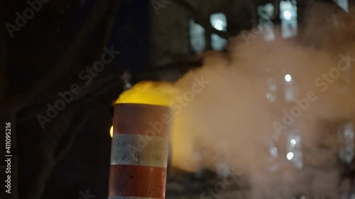 Steam heating escaping chimney in NYC at night. Traffic light behind fog in Manhattan New York City.